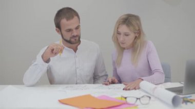 Masada oturan ve planları inceleyen iki ciddi Kafkasyalı profesyonel. Genç güzel bir kadın ve yakışıklı bir adam el sıkışıyor, erkek tasarımcı göz kırpıyor. Başarılı işbirliği, yaratıcı çalışma.