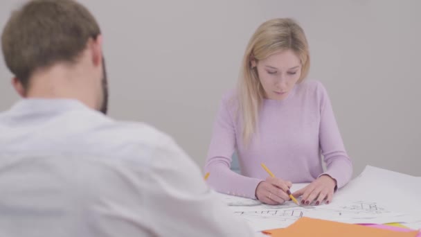 Portrait of confident Caucasian woman drawing blueprint, shaking colleagues hand and smiling. Professional designer working in the office. Specialist implementing ideas on paper. — Stok video