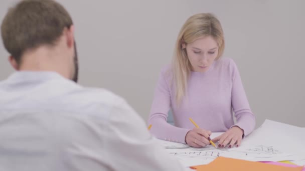 Portrait of confident Caucasian woman drawing blueprint, shaking colleagues hand and smiling. Professional designer working in the office. Specialist implementing ideas on paper. — стокове відео