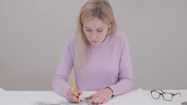 Portrait of concentrated Caucasian woman drawing blueprint, doing mistake and breaking pencil. Irritated female designer having problems with idea implementation. Professional at workplace. — Stock Video