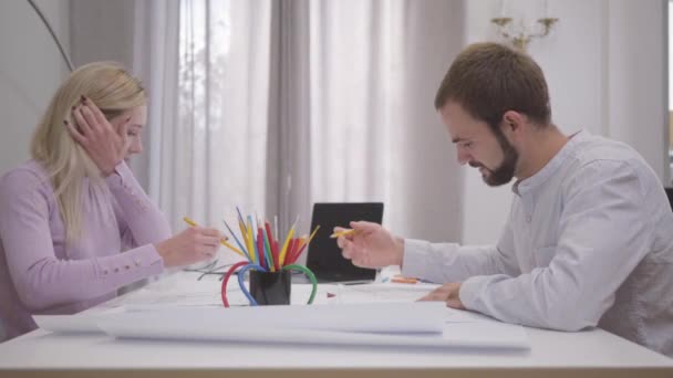 Двоє білих кавказьких архітекторів завершили свій проект і дали п'ять. Посміхаючись, молодий чоловік і жінка втілюють ідеї на папері. Творча архітектурна робота, професійна професія.. — стокове відео