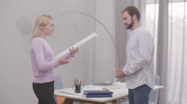 Genç ve çekici beyaz bir mimar müşteriye proje veriyor ve beşlik çakıyor. Memnun müşteri ve profesyonel bayan tasarımcı işbirliğini bitiriyor. Başarılı insanlar, yaratıcı işler..