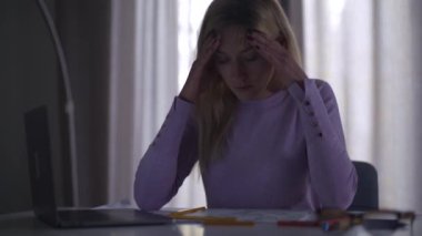 Masada oturan, alnını ve şakaklarını ovuşturan yorgun, beyaz bir kadın. Akşamki yeni proje üzerinde çalışan kadın bir uzman. Güzel profesyonel mimar çok çalışıyor..