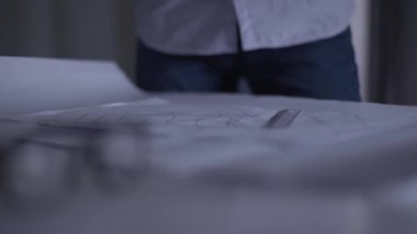 Masanın üzerinde duran mimari çizimlerin yakın çekimi. Sinirli adam onlara öfkeyle yumruk atıyor. Tasarım kavramı ile ilgili sorunlar, projenin uygulanması.