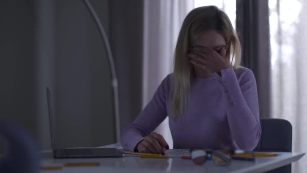 Young exhausted Caucasian girl rubbing eyes and looking at the laptop screen. Female specialist working on the new project in the evening. Beautiful professional architect overworking. — Stock Video