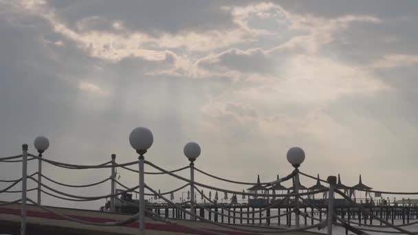 Kamera, die sich von einer hölzernen Strandrampe in den wolkenverhangenen Himmel bewegt. Sonnenstrahlen brechen durch die Wolken. Düsterer Sommertag im Ostseebad. wunderschöne türkische Natur. — Stockvideo