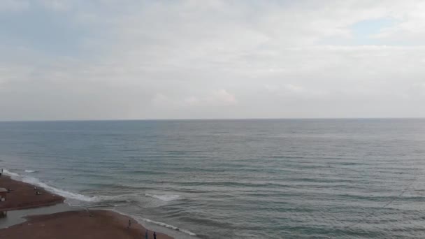 Вид сверху на песчаный восточный пляж с несколькими неузнаваемыми людьми, стоящими там. Спокойные средиземноморские волны, разбивающиеся на побережье. Аэросъемка идеальной турецкой природы . — стоковое видео