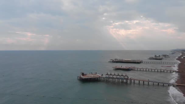 Luftaufnahme von hölzernen Strandrampen im Mittelmeer. Sonnenstrahlen brechen durch schwere Wolken. Düsterer Sommertag im Ostseebad. wunderschöne türkische Natur. — Stockvideo