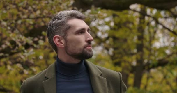 Portrait of an adult Caucasian tourist standing in the forest and fixing his jacket. Confident man in casual clothes enjoying calm quiet autumn day outdoors. Cinema 4k footage ProRes HQ. — Stock Video