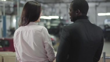 Melez bir çiftin galeride yeni bir araba seçmesi. Genç Afrikalı Amerikalı bir adam güzel beyaz bir kadına sarılıyor ve gülümsüyor. Çok ırklı bir aile arabası. Araba bayiliği, araba işi..