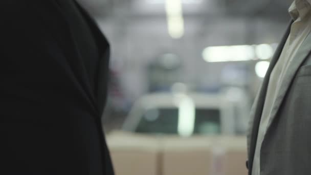Close-up van twee mannen die elkaar de hand schudden in de showroom. Man Afro-Amerikaanse hand geven autosleutels aan de koper. Blanke man koopt nieuwe auto bij de dealer. Autohandel, autohandel, handdruk. — Stockvideo