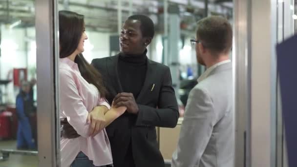 Famiglia birazziale positiva che si abbraccia nella concessionaria di auto. Un giovane venditore che parla con la coppia felice. Uomo afroamericano e bella donna caucasica che compra auto. Concessionaria auto, industria automobilistica . — Video Stock