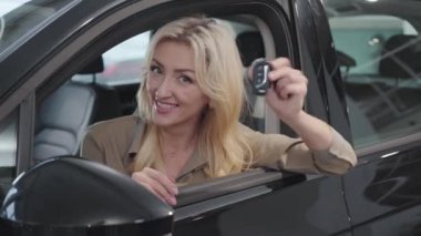 Kuaförde otururken araba anahtarlarıyla böbürlenen kahverengi gözlü, beyaz, sarışın kadın. Başarılı bir iş kadını galeride araba alıyor. Araba bayiliği, araba işi..