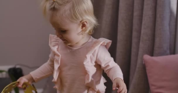 Close-up van een schattig blond blank kind dat thuis met een speelgoedkroon speelt. Mooi meisje in roze blouse, thuis bij moeder. Gelukkige kindertijd, vrije tijd binnen. Bioscoop 4k beelden Prores Hq. — Stockvideo