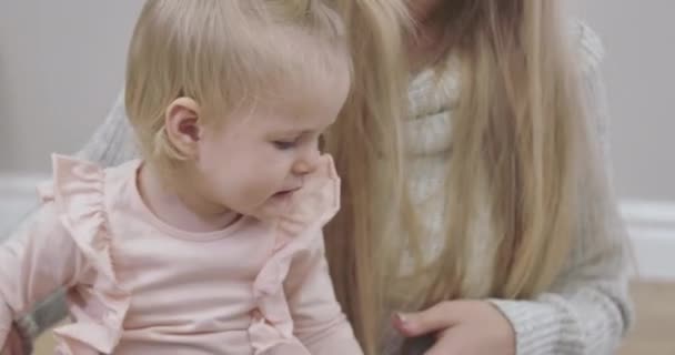 Cara de cerca de la hermosa niña rubia caucásica con encantadores ojos grises. Madre joven aplaudiendo a sus hijas. Feliz paternidad, alegría de maternidad. Cinema 4k metraje ProRes HQ . — Vídeo de stock