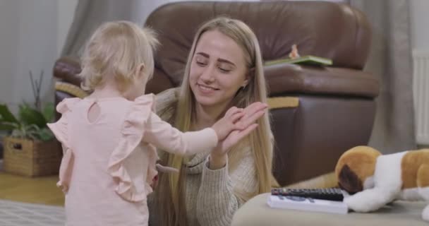 Retrato de mujer caucásica feliz cogida de la mano de niña y sonriente. Lindo bebé alejándose con un juguete suave. Alegría de maternidad, paternidad feliz. Cinema 4k metraje ProRes HQ . — Vídeos de Stock