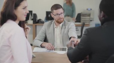 Kızıl sakallı, beyaz bir menajer müşteriye arabanın anahtarlarını veriyor ve elini sıkıyor. Başarılı bir Afrikalı Amerikalı müşteri güzel eşine ya da kız arkadaşına anahtar veriyor. Araba galerisi, araba işi..