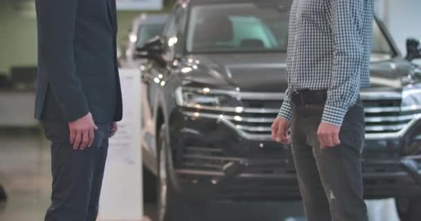 Close-up of unrecognizable male Caucasian dealer giving car keys to male customer and shaking his hand. Adult male car dealer making sale-purchase deal. Car business. Cinema 4k footage ProRes HQ. — Stock Video