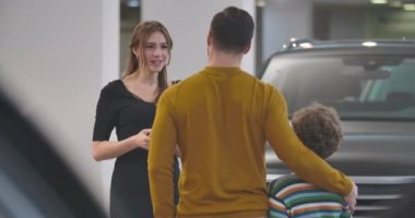 Beyaz kadının erkek müşteriye özelliklerini açıklayan ve elini sıkan yakın çekimi. Yetişkin bir adam oğluyla araba alıyor. Araba galerisi, araba işi. Sinema 4k görüntüleri Prores Hq.