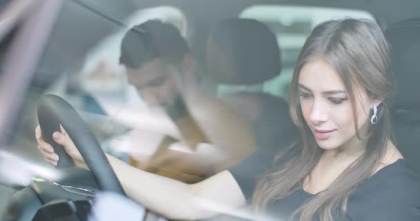 Vista lateral de la hermosa mujer caucásica sentada en el asiento de los conductores y mirando alrededor del salón. Joven chica atractiva elegir nuevo automóvil en la concesionaria de automóviles. Cinema 4k metraje ProRes HQ — Vídeos de Stock