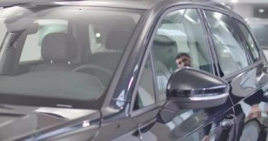Ciddi bir beyaz adam arabaya geliyor, kapıyı açıyor ve kuaföre giriyor. Kendine güvenen bir iş adamı ya kendi arabasında oturuyor ya da kiralık. Araba galerisi, araba işi. Sinema 4k görüntüleri Prores Hq.