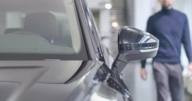 Bulanık beyaz sakallı adam siyah arabaya doğru geliyor ve kuaföre giriyor. Sahibi otoparkta otomobilde oturuyor. Araba işi. Sinema 4k görüntüleri Prores Hq.