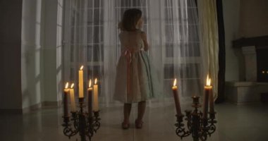 Kamera, mum ışığında elinde oyuncak bebekle beyaz bir kıza yaklaşıyor. Garip çocuk oyuncağını okşuyor ve etrafa bakıyor. Korku, korku, tuhaflık..