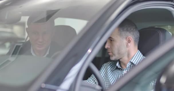 Close-ip side view of Caucasian man sitting in car salon and making sale purchase deal. Male car dealer explaining specifications to the customer. Car business. Successful Cinema 4k footage ProRes HQ. — 비디오