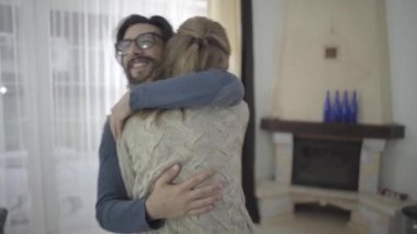Mutlu beyaz çift evde sarılıyor ve dönüyorlar. Gözlüklü, gülümseyen sakallı adam sevimli karısını ya da kız arkadaşını kucaklıyor. İyi ilişki, mutluluk..