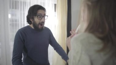 Hamilelik testine bakıp karısını ya da kız arkadaşını öpen mutlu sakallı beyaz adamın yakın çekimi. Mutlu çift iyi haberlerin tadını çıkarıyor. Hamileliğin neşesi.