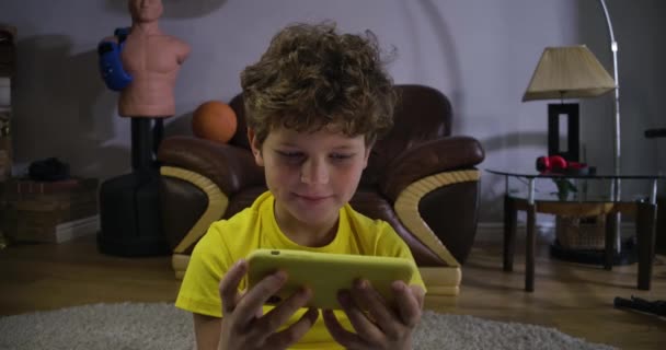 Rostro de niño caucásico enfocado viendo dibujos animados o películas en la pantalla del teléfono inteligente. Niño con el pelo rizado absorbido por Internet. Redes sociales, tecnologías modernas. Sede del cine 4k ProRes . — Vídeo de stock