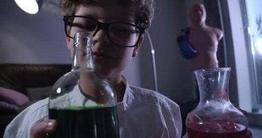 Kafkasyalı genç kimyagerin kimyasalları koklamasına yakın çekim. Laboratuvar önlüklü kıvırcık saçlı çocuk sıvılarla dolu şişelere bakıyor. Zeka, kimya, deha, nesil Z. Cinema 4k Prores Hq.