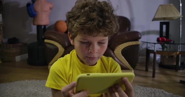 Close-up gezicht van Kaukasische krullende jongen kijken comedy show op smartphone scherm. Joyuful kind lachen. Generatie Z, sociale media, internet, moderne technologieën. Bioscoop 4k Prores Hq. — Stockvideo