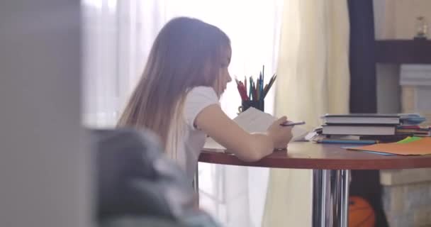 Vista posterior de buena chica caucásica de pie y salir con libro de ejercicios. Niño inteligente haciendo la tarea los fines de semana en casa. Inteligencia, educación, estudio de conceptos. Sede del cine 4k ProRes . — Vídeos de Stock