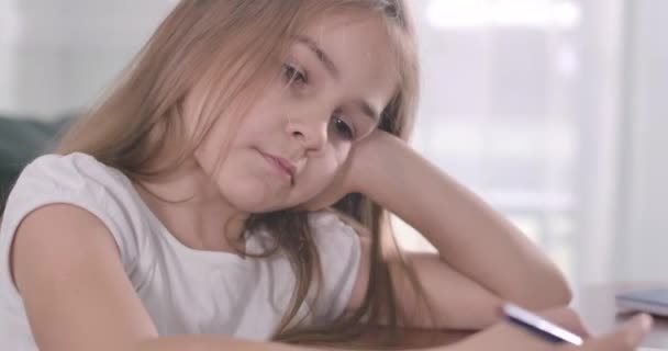 Een close-up van een mooi blank meisje met een hoofd in de hand. Moe slaperig schoolkind zittend aan tafel in het zonlicht. Overwerken, studeren, onderwijs. Bioscoop 4k Prores Hq. — Stockvideo