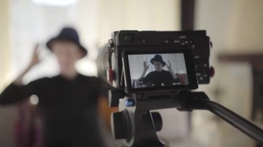 Son sınıf beyaz kadının zarif şapkalarını değiştirdiğini gösteren video kamera görüntüleri. Olgun kadın blogcu video kaydediyor. Teknolojiler, blog yazma, sosyal medya.