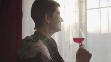 Şarap kadehi tutan ve pencereden dışarı bakan son sınıf beyaz kadının yüzü. Akşamları gülümseyen yorgun bayanın portresi. Kendine güven, dinlenme. Boş zaman.