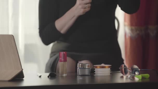 Gros plan d'une table avec des cosmétiques. Femme blanche méconnaissable assise et faisant du maquillage. Mode, beauté, soin du visage, soin de la peau . — Video