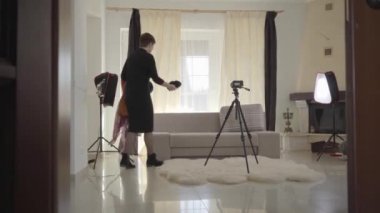 Son sınıftaki bayan kanepeye gelip üzerine şapkalar ve eşarplar takıyor. Etrafta kameralar var. Olgun beyaz kadın blogcu video kaydı için hazırlanıyor. Çevrimiçi, canlı, günlük.