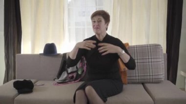 Olgun bir kadının kameraya el sallayıp zarif şapkalar ve eşarplar gösterdiği yakın çekim. Son sınıf kadın video blogcusu moda ve aksesuarlardan bahsediyor. Modern meslekler, online teknolojiler..