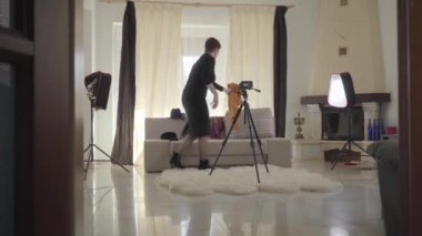 Güzel esmer, beyaz bir kadın kanepeye oturmuş zarif eşarplarla kaplanmış ve kameraya bakıyor. Üst düzey kadın blogcu video kaydı için hazırlanıyor. Çevrimiçi, canlı, günlük.