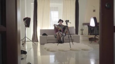 Kameranın önünde oturmuş modadan bahseden güzel olgun bir kadının kapısından ateş etmek. Şık bir kıyafet içinde video blogunda yetişkin bir beyaz kadın. İnternet, çevrimiçi, günlük.