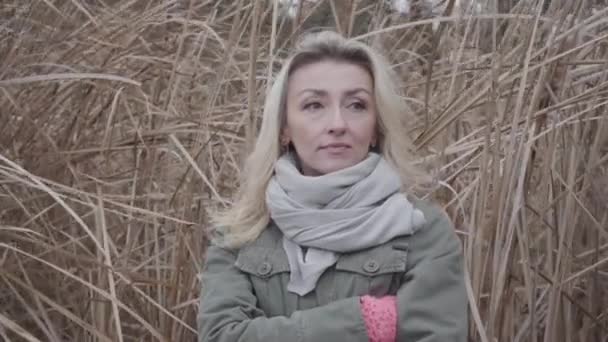 Close-up van trieste blanke vrouw die op de achtergrond staat van gele herfststruiken. Charmant meisje met blond haar en bruine ogen buiten wachten. — Stockvideo