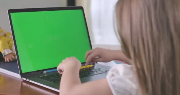Közelkép a fehér iskolás gyerekről, aki zöld képernyős laptopon gépel. Online tanuló vagy közösségi médiát használó lány. E-tanulás, online, internet, oktatás, függőség. Mozi 4k Prores Hq. — Stock videók