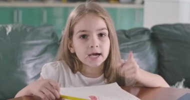 Güzel beyaz kız kameraya bakıyor ve konuşuyor. Parmaklarında figürler gösteren sevimli bir çocuk. Matematik problemi olan kağıt masada yatıyor. Çocuk problem çözmeyi açıklıyor. Sinema 4k Prores Merkezi.