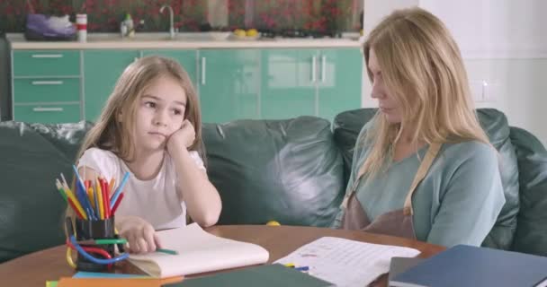 Menina caucasiana preguiçosa sentada à mesa sem querer estudar. Jovem mãe tentando ajudar a filha a fazer os trabalhos de casa. Conceito de educação, inteligência, apoio. Cinema 4k ProRes HQ . — Vídeo de Stock