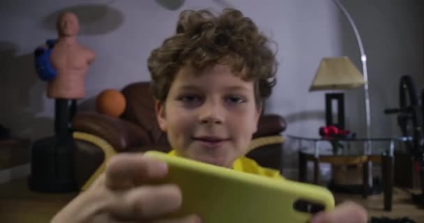 Κοντινό πλάνο ενός Καυκάσιου έφηβου με κόκκινα μάτια που παίζει βιντεοπαιχνίδια. Χαριτωμένο σγουρομάλλικο αγόρι που χρησιμοποιεί smartphone και κοιτάζει μπροστά. Online παιχνίδια, τεχνολογίες, παραγωγή Z. Κινηματογράφος 4k Prores Hq. — Αρχείο Βίντεο