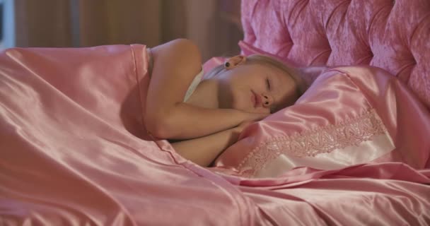 Primer plano de linda niña caucásica durmiendo en la cama rosa. Niño cansado descansando en casa. Niñez despreocupada . — Vídeo de stock