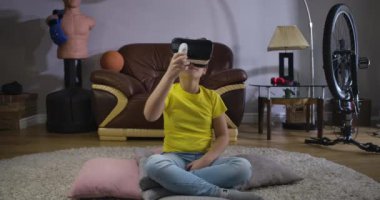 Vr kulaklıklı, saçları kıvırcık, uzaktan kumandalı ve etrafa bakan beyaz bir genç. Sanal gerçekliği kullanan bir çocuk. Artırılmış gerçeklik, VR gözlükleri, Z. Cinema 4k Prores Hq nesli..