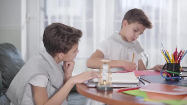 Sidovy över lilla kaukasiska pojke väntar på tvillingbror att rita bilden och ge high five. Smarta syskon som gör läxor hemma. Generation Z, klartänkt, utbildningskoncept. — Stockvideo